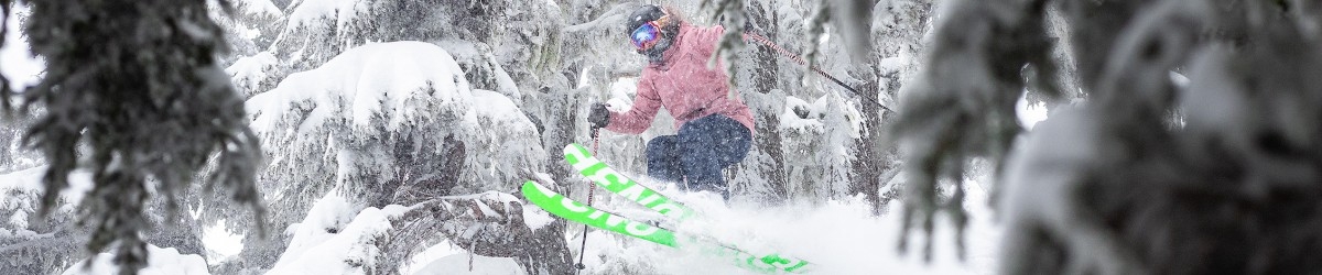 LONE SKIER IN PINK COAT JUMPING THROUGH POWDER SNOW