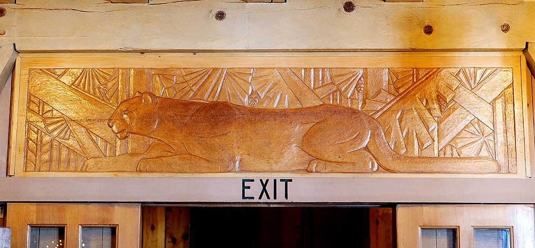 CARVED WOOD PANEL OF COUGAR RESTING IN THE FOREST