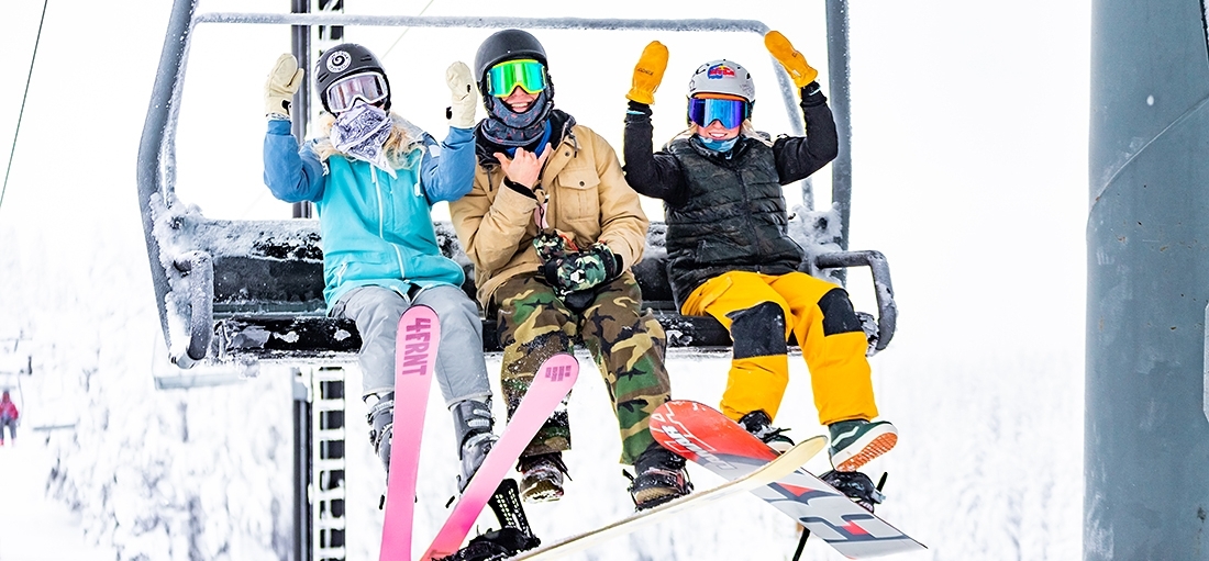 THREE SKIERS AND SNOWBOARDERS ON TIMBERLINE CHAIR LIFT