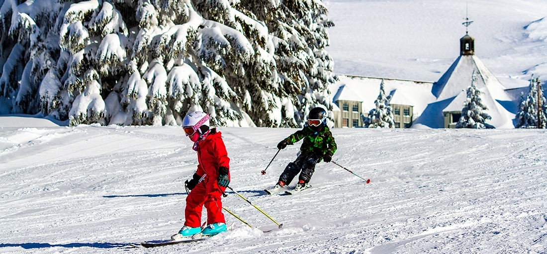 TWO CHILDREN SKIING IN FRONT OF TIMBERLINE