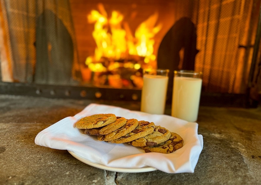 COOKIES ON A PLATE, TWO GLASSES OF MILK, IN FRONT OF A FIREPLACE