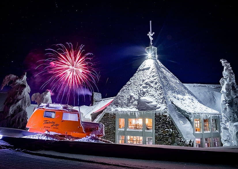 NEW YEAR'S EVE FIREWORKS SEEN FROM BEHIND SNOWY TIMBERLINE LODGE WITH A VINTAGE TUCKER SNOWCAT IN THE FOREGROUND