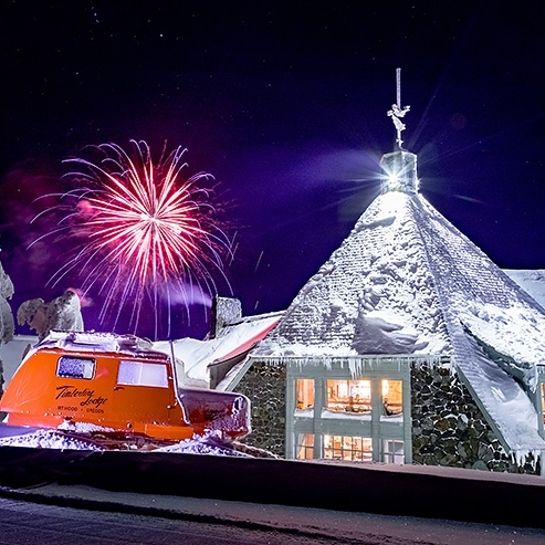 PINK FIREWORKS GOING OFF IN FRONT OF TIMBERLINE LODGE WITH ORANGE TUCKER SNO-CAT IN FOREGROUND