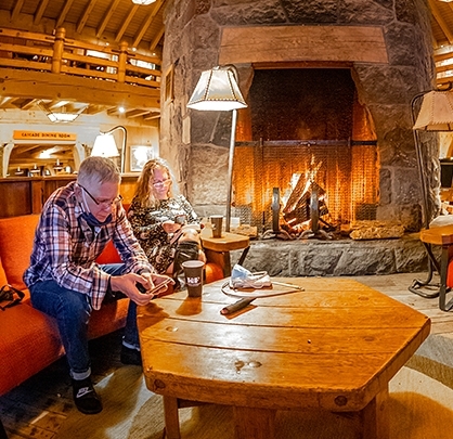 TIMBERLINE HOTEL GUEST LOOKING AT SMARTPHONE IN FRONT OF FIREPLACE