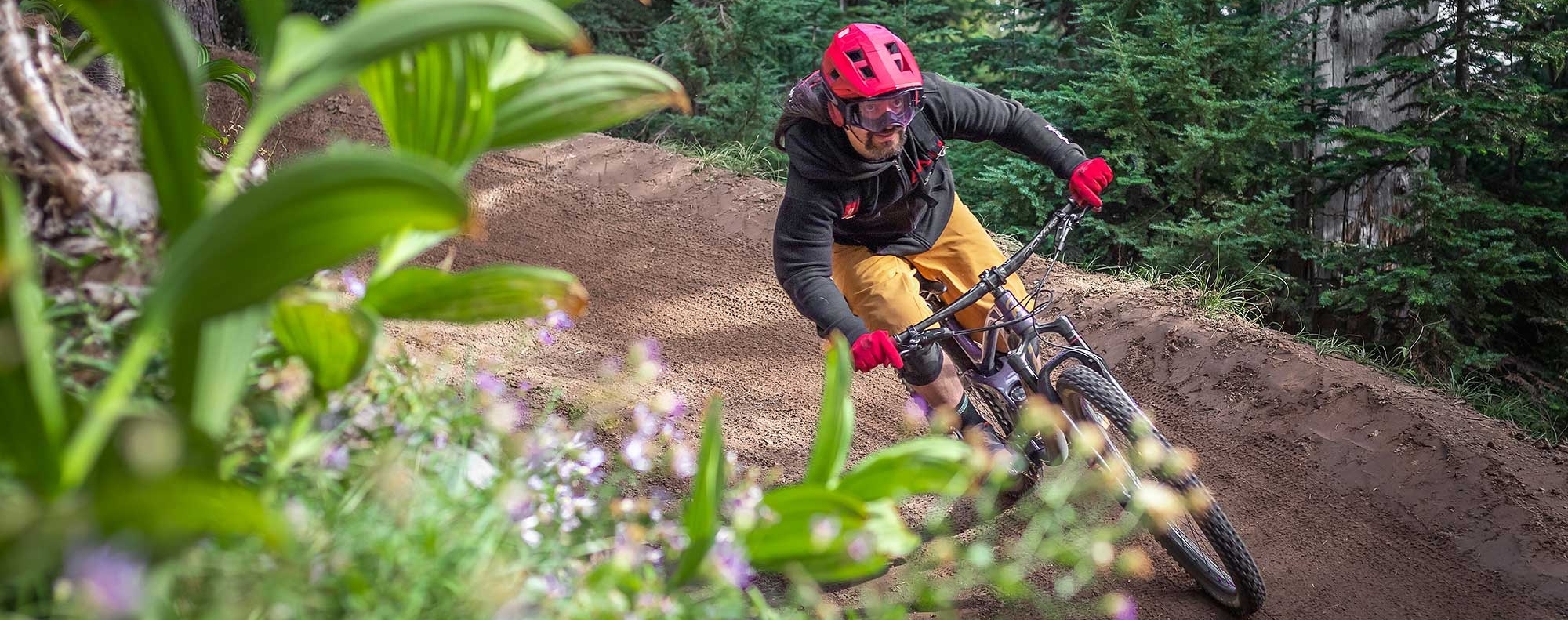 Mountain biker in a red helmet and gloves riding around a bend at the Timberline Bike Park