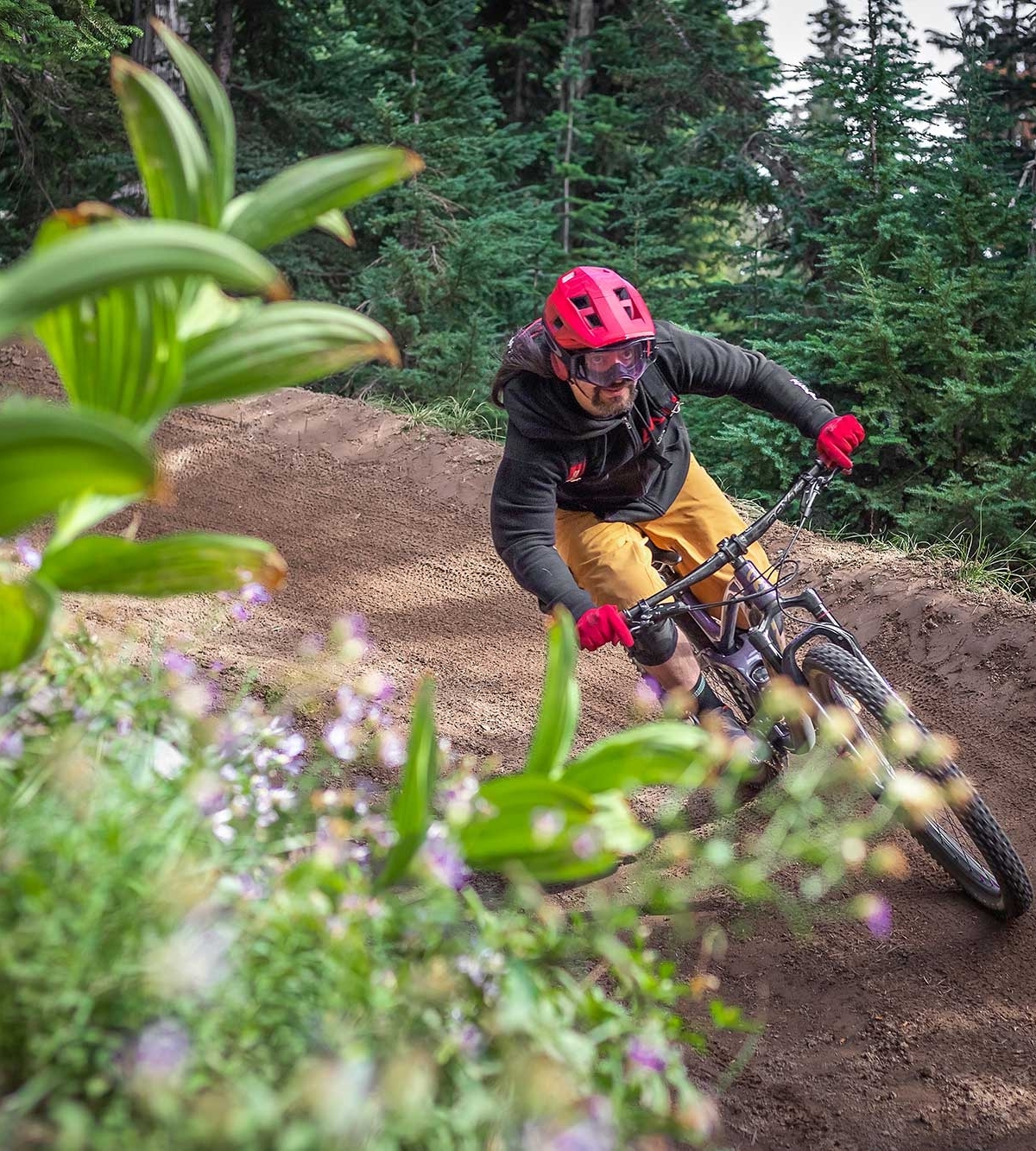 Mountain biker in a red helmet and gloves riding around a bend at the Timberline Bike Park