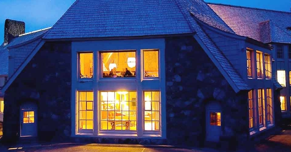 DUSK VIEW FROM BACK PATIO INTO WELL-LIT LODGE WINDOWS