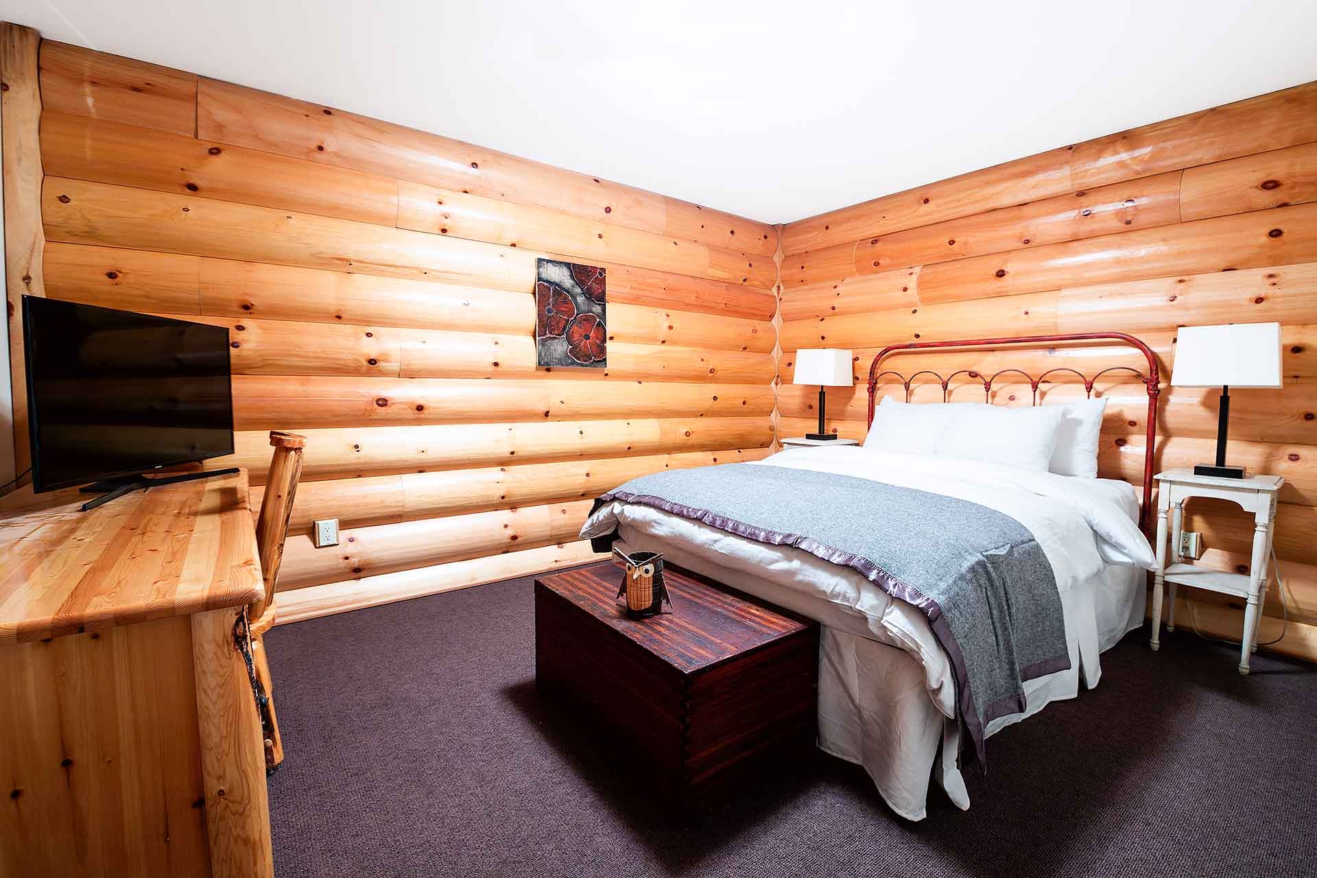 LAGC UNIT 2 UPSTAIRS BEDROOM WITH LOG PANELING ON THE WALLS AND A QUEEN BED