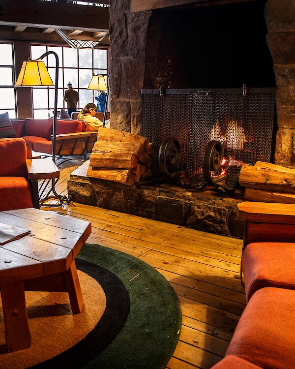 A roaring fire in the massive fireplace, surrounded by couches and a table in the Timberline Main Headhouse